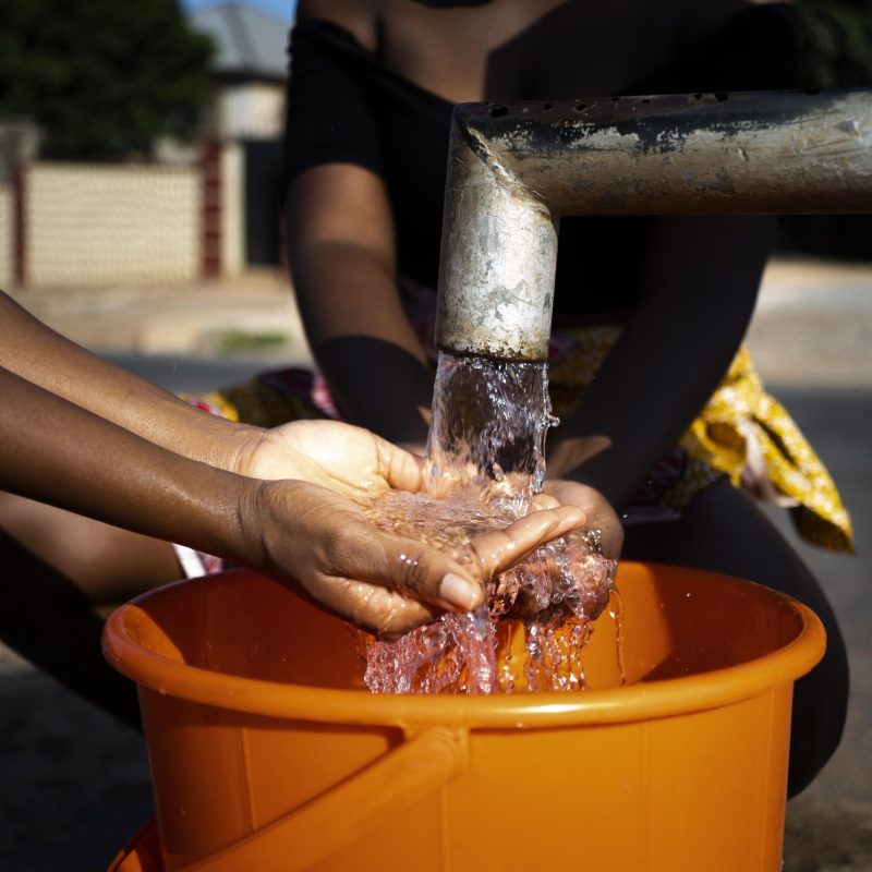 african-woman-pouring-water-recipient-outdoors